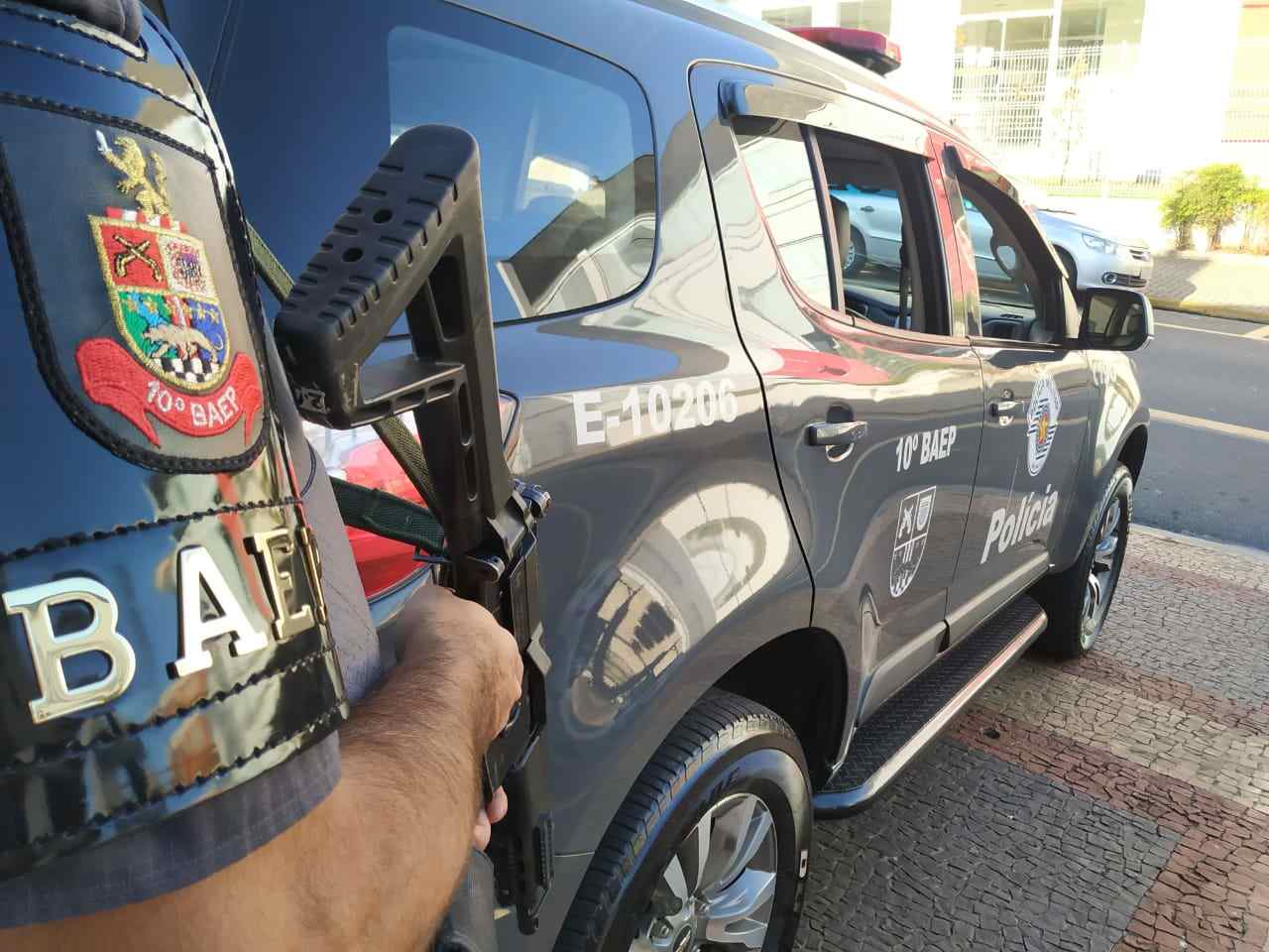 Na imagem temos um policial do BAEP armado ao lado da viatura E-10206