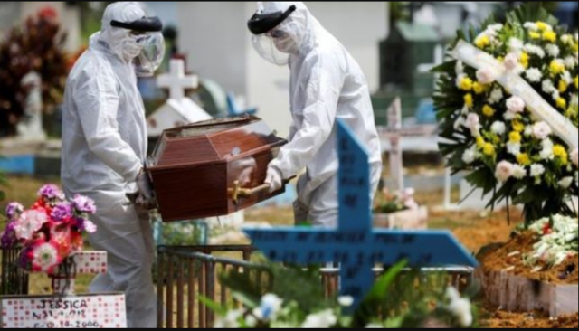 Na imagem vemos um enterro de COVID, com os coveiros com EPI