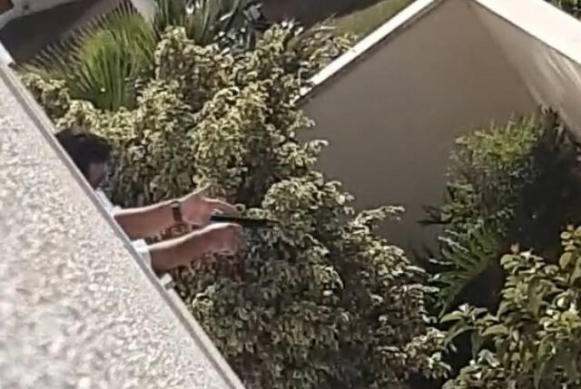 Uma foto do homem segurando a arma e atirando do apartamento
