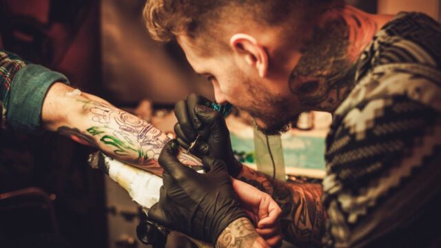 Uma foto de um tatuador fazendo uma tatuagem no braço do cliente Uma foto de um tatuador fazendo uma tatuagem no braço do cliente