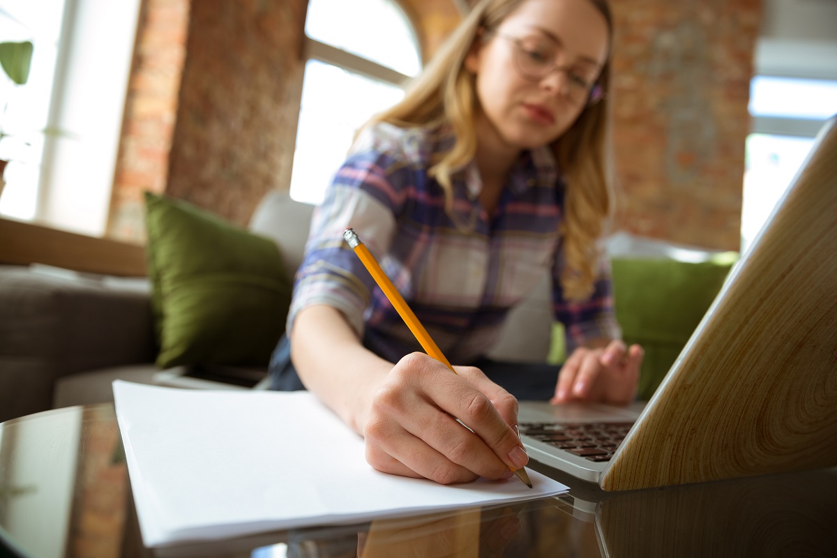 Young woman studying at home during online courses or free information by herself. Becomes musician, violinist while isolated, quarantine against coronavirus spreading. Using laptop, smartphone, headphones.