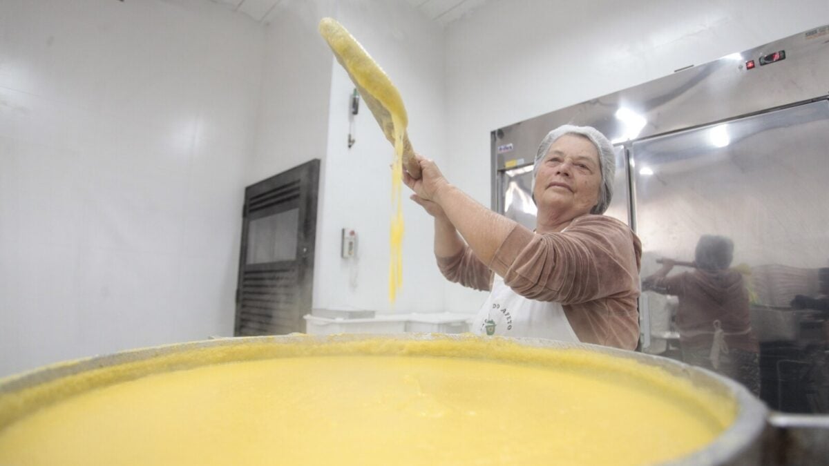 Voluntária prepara polenta em uma grande panela para a Festa da Polenta de Santa Olímpia